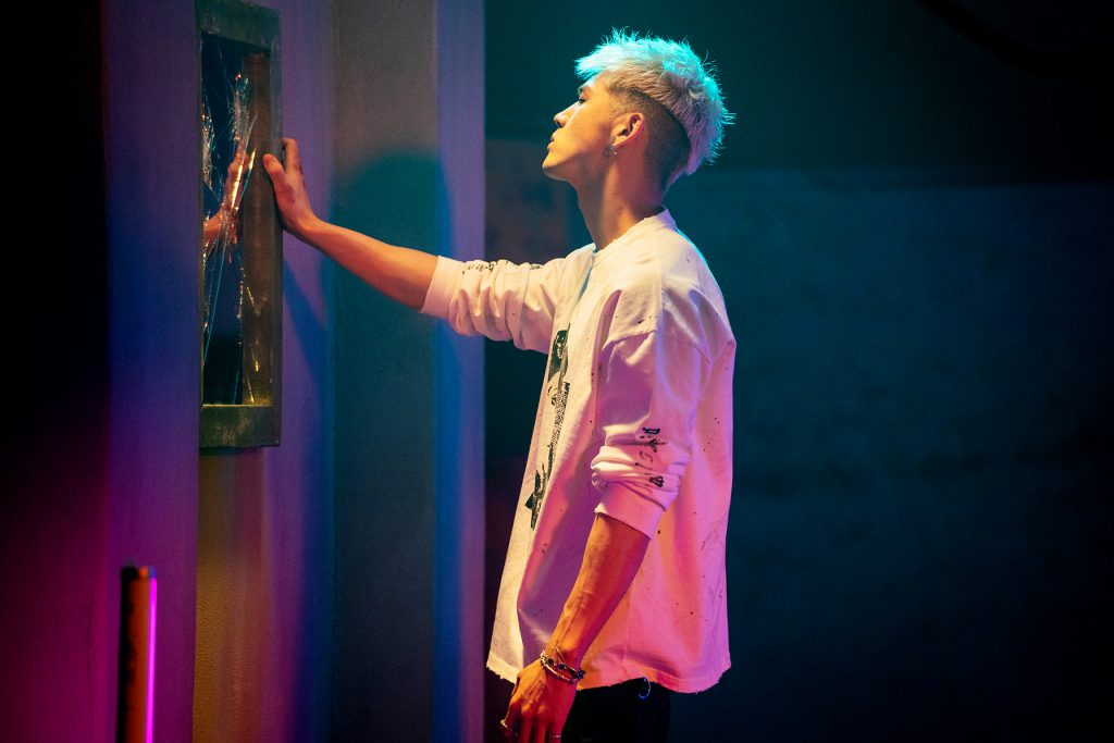 BM of KARD stands at a smashed mirror looking into it during his "Broken Me" Music video produced by 8Pex and Vive studios