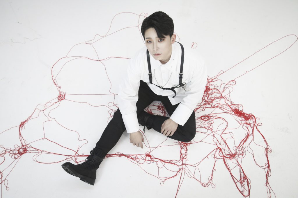 Photo of VOID's drummer Shin wearing a white and black outfit sitting on a white floor surrounded by red string.
