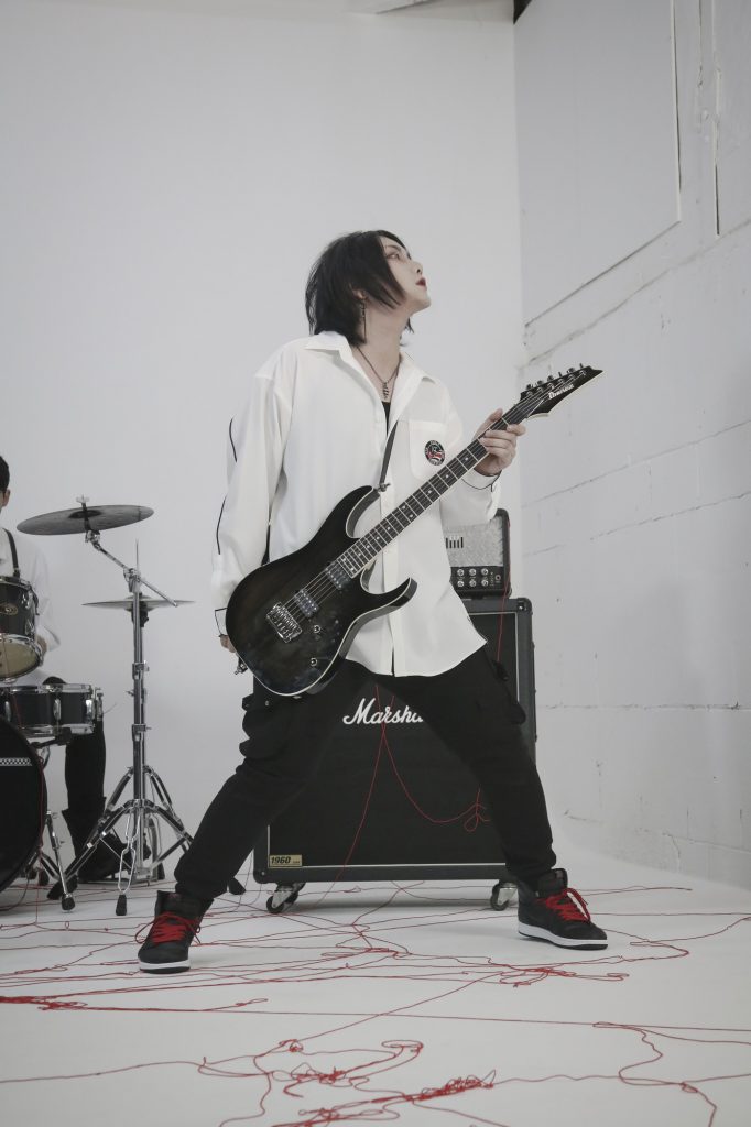 Photo of VOID's guitarist J.Robyn performing with his guitar in a white room.
